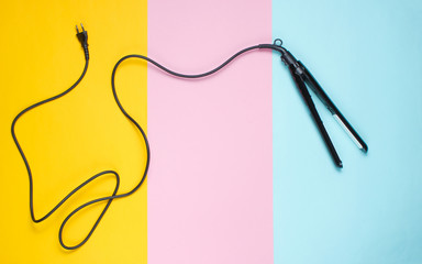 Hair style. Hair straightener on colored paper background. Top view, minimalism.