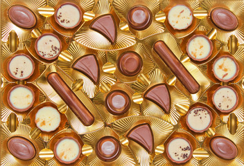 Golden tray withpalette.palette of chocolate candies close up, top view.