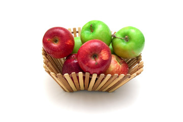 Red and green apples in a basket on white background.