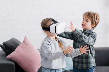 adorable siblings playing with virtual reality headset at home