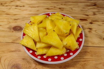 Pieces of pineapple in a plate on wooden table