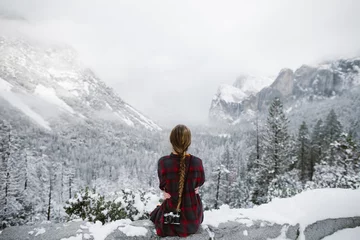 Fotobehang woman with camera sitting looking at tunnel view in yosemite in winter © Eastlyn Bright