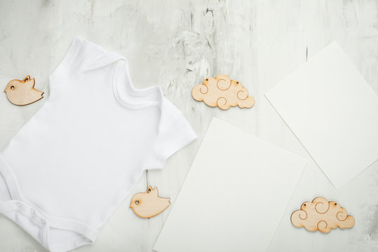 Layout Flat Lay a white children's body shirt, on a white background, with white postcards and children's wooden toys. Choose design and placement of logos, advertising