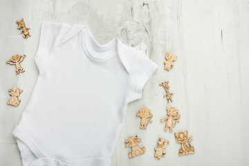 Layout Flat Lay white baby bodysuit shirt, on a white background with children's wooden toys. Mock up for design and placement of logos, advertisements