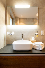Close-up view of bathroom sink , shelf, towels and soap dispenser