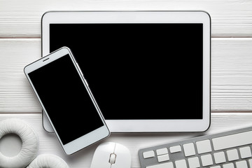 White modern smartphone and digital tablet, headphones, computer mouse and keyborad on white background