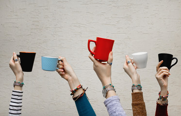 Many different hands holding coffee cups.