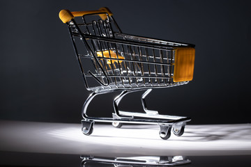 Empty shopping trolley on dark toned foggy background with some copy space.