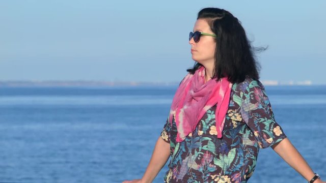 4K Close up shot of a attractive woman in red scarf standing on the seaside beackground