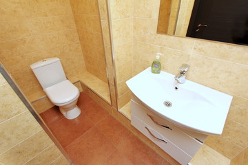 Modern spacious bathroom with bright tiles with toilet and sink. Side view