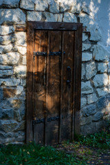 Stone wall and antique wooden door in the garden.
