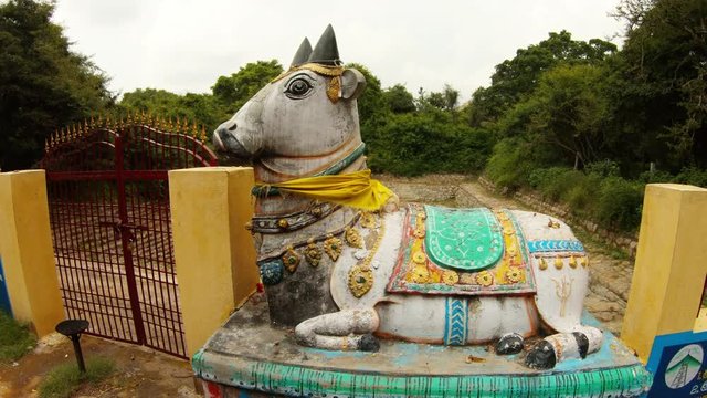 Statue of bull Nandi near gate to Ancient hand-made pond among jungle