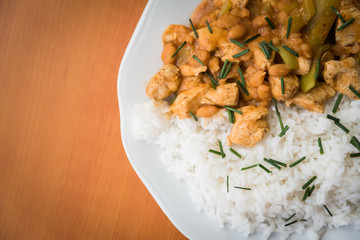 Chicken curry nuggets with rice and bean on a white plate. Space on left side