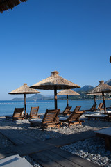 Bamboo umbrellas and wooden deck chairs on the sandy beach by the sea