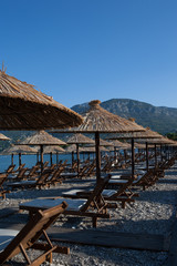 Bamboo umbrellas and wooden deck chairs on the sandy beach by the sea