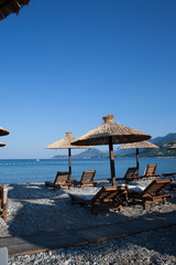 Bamboo umbrellas and wooden deck chairs on the sandy beach by the sea