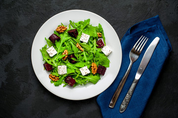 Salad of arugula, cheese, beet, walnut, on the background of slate, stone or concrete.