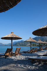 Bamboo umbrellas and wooden deck chairs on the sandy beach by the sea
