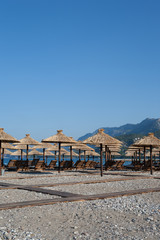 Bamboo umbrellas and wooden deck chairs on the sandy beach by the sea