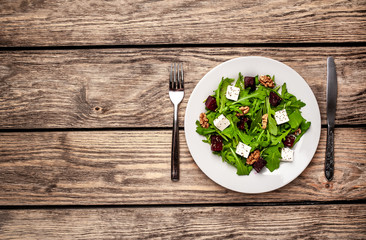 Salad of arugula, cheese, beet, walnut, on a wooden table