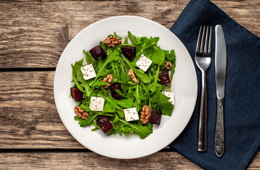 Salad of arugula, cheese, beet, walnut, on a wooden table