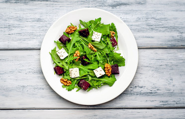 Salad of arugula, cheese, beet, walnut, on a wooden table