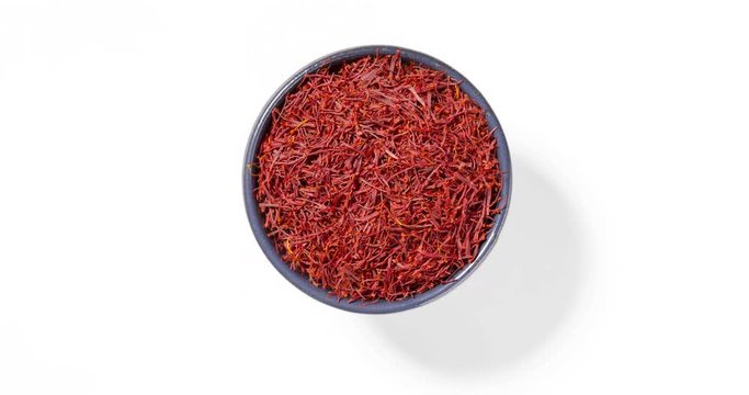 Safran threads spice in round bowl on white background, seamless loop, view directly from above.