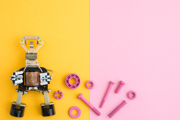 Metal robot, screws and washers, spring, colored with multicolored paint. Colorful background. Pink...