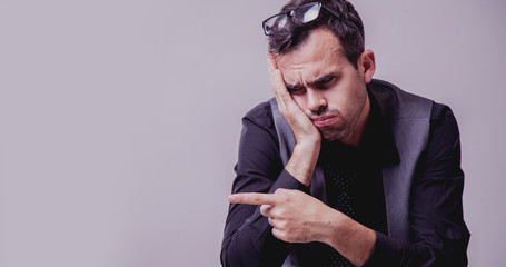 Stress for professional burnout. Portrait of exhausted and tired businessman pointing with finger towards copy space area.