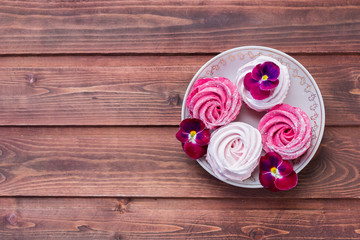 Homemade pink marshmallow from currant on a wooden background with pink flowers, home zephyr.Still life with pansy, heartsease and zephyr.sweets, proper nutrition without sugar.Copy space