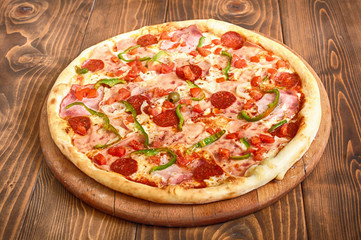 Pizza pepperoni with tomatoes, bacon and olives, side view