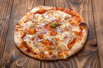 Tuna and red onion pizza on wooden background, side view