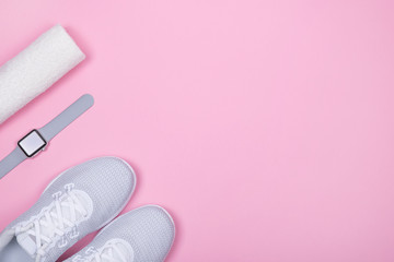 White sport shoes (sneakers) with smart watch (activity tracker) and towel on pink color background. 