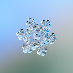 Snowflake sparkling on smooth gradient background. Macro photo of real snow crystal: elegant star plate with fine hexagonal symmetry, short ornate arms, glossy relief surface, complex inner pattern.