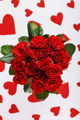 Fototapeta na wymiar Red roses and hearts on a white wooden table. Concept of Women's Day or St. Valentine. Copy space.