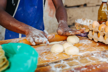 Man rolling out dough to make traditional flat bread on a table in Uganda, Africa.