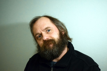 Emotional portrait of a bearded man of 50 years. Wrinkles on the forehead of a man. Sad look.