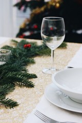 Table ready for a festive dinner with white plates and wine glass