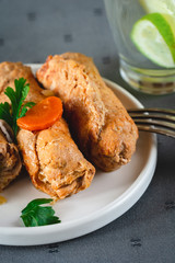 Pork roulades with bacon, carrot, cucumber and onion served on plate.