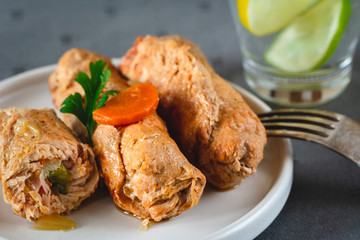 Pork roulades with bacon, carrot, cucumber and onion served on plate.