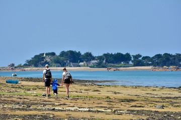 Un couple et un petit garçon qui se promènent sur le sable dans la baie de Pellinec à Penvénan en Bretagne. France