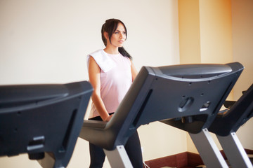 Concept of sport and healthy lifestyle. Young attractive fitness woman running on treadmill, wearing in white sportswear. Healthy sporty woman doing cardio exercise on treadmill