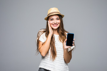 portrait of a casual pretty woman in hat winking blank mobile phone screen isolated over gray background