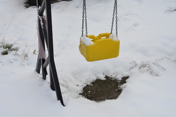 an empty swing under the snow