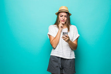 Contented smiling woman typing text message or scrolling through social networks using smartphone isolated over blue background