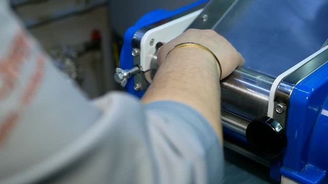 Chef making dough pastry sheeter. Baker forming shaping dough rolled pastry metal work table closeup hands process of preparing bread khinkali dough roller machine thin pasta sheet