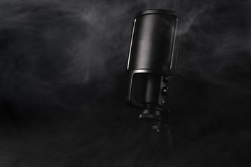 Black microphone on a black background with smoke