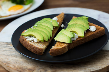 Breakfast sandwich on toast bread made with fresh sliced avocado, cream cheese and seeds, from above