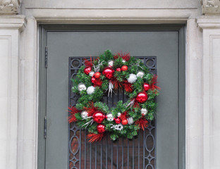 front door with Christmas wreath made of pine branches and red berries and shiny balls