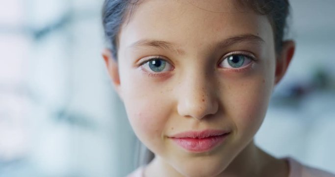 Close up portrait of a little girl with blue eyes looking in the camera on daylight background. Shot with RED camera in 8K. Concept of childhood, kids protection, daughter, happy family